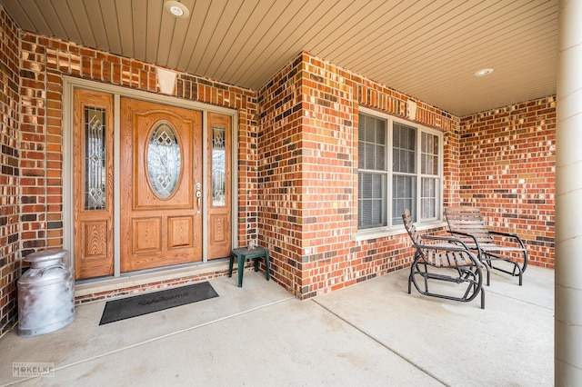 property entrance with a porch and brick siding