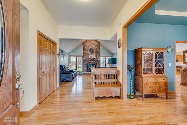 entrance foyer with lofted ceiling, light wood-style floors, and a fireplace