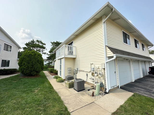 view of property exterior featuring a garage, a yard, a balcony, and central air condition unit