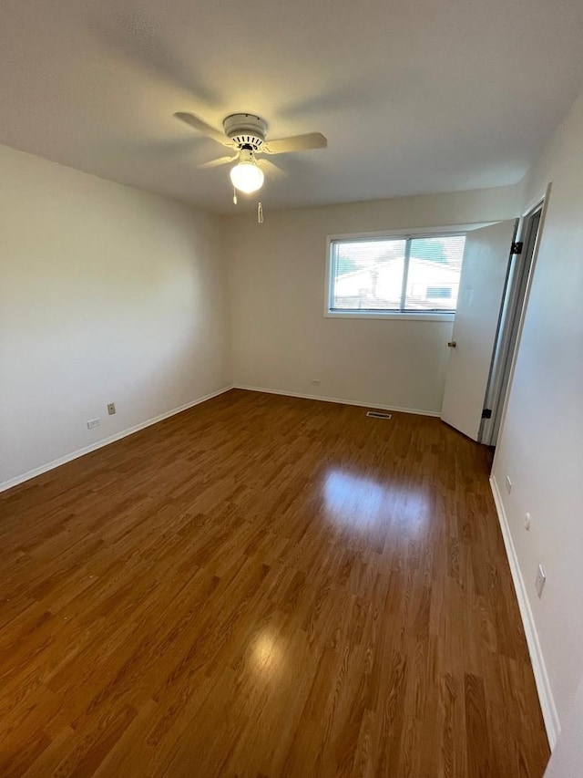 empty room featuring visible vents, wood finished floors, a ceiling fan, and baseboards