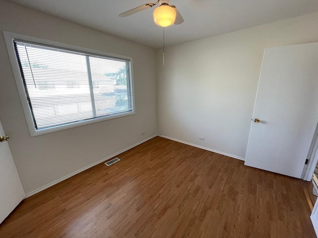 unfurnished room with ceiling fan, wood finished floors, visible vents, and baseboards