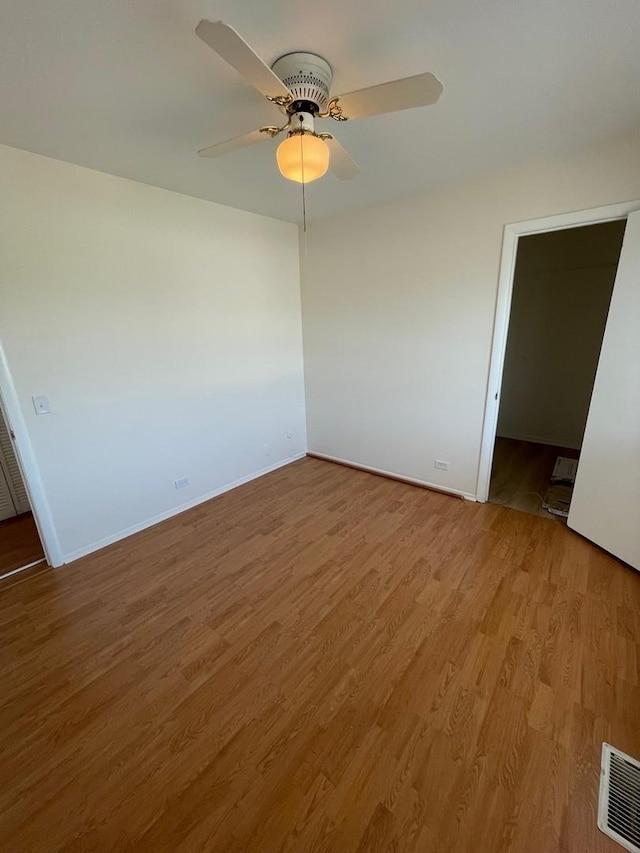 spare room featuring light wood-style floors, baseboards, visible vents, and a ceiling fan