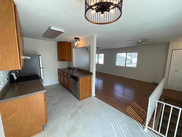 kitchen featuring a sink, range with gas stovetop, stainless steel dishwasher, brown cabinetry, and dark countertops