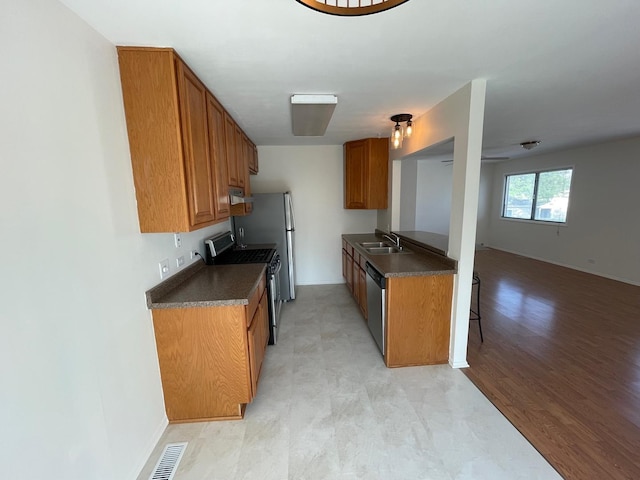 kitchen with dark countertops, visible vents, appliances with stainless steel finishes, and brown cabinetry