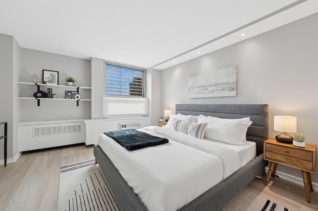 bedroom with radiator, light wood-style flooring, baseboards, and recessed lighting