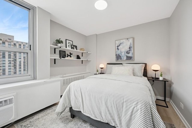 bedroom featuring radiator, baseboards, and wood finished floors