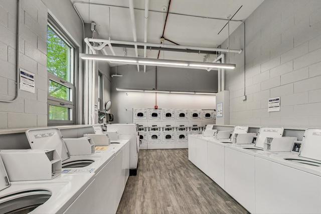 community laundry room featuring concrete block wall, washer and clothes dryer, and wood finished floors