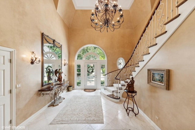 foyer with a towering ceiling, baseboards, ornamental molding, stairway, and an inviting chandelier