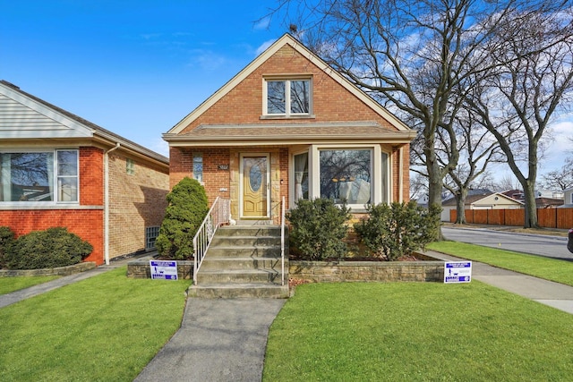 bungalow featuring a front yard, fence, and brick siding