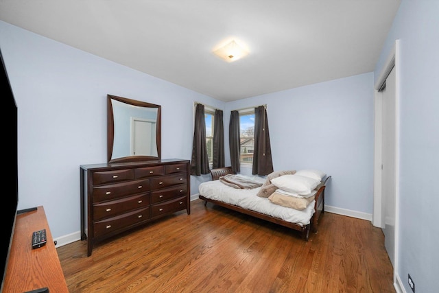 bedroom with a closet, baseboards, and wood finished floors