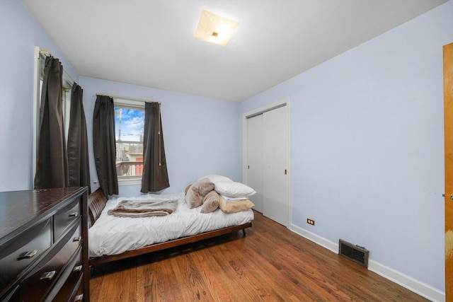 bedroom featuring a closet, visible vents, baseboards, and wood finished floors