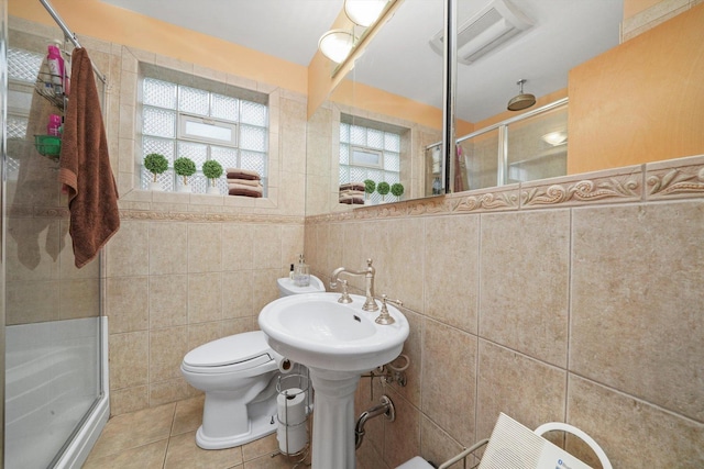 full bath with toilet, a stall shower, tile walls, and tile patterned floors