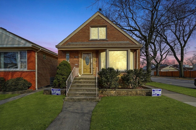 view of front of home with brick siding and a yard