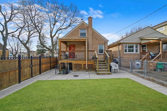 rear view of property with a yard, brick siding, and a fenced backyard