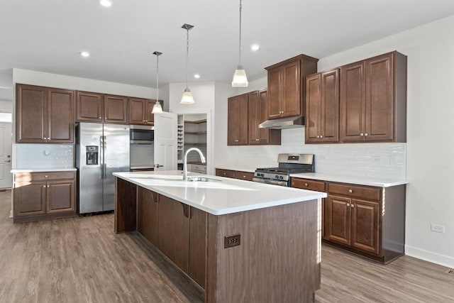 kitchen with stainless steel appliances, light wood finished floors, light countertops, and under cabinet range hood