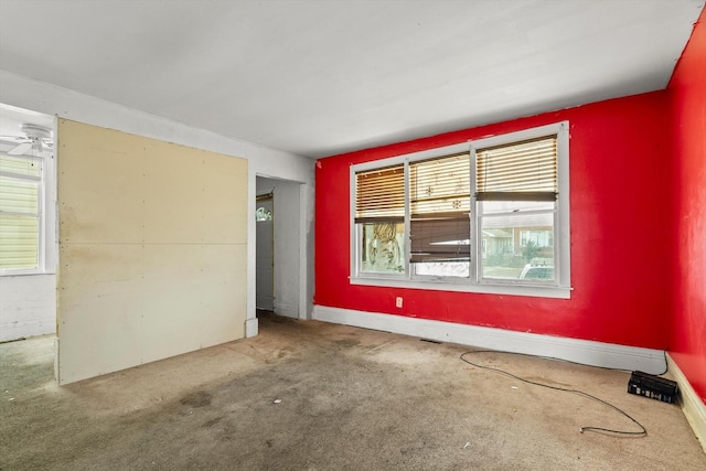 carpeted empty room featuring ceiling fan and baseboards