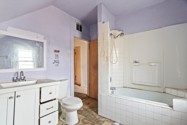 bathroom featuring toilet, tiled shower / bath combo, visible vents, vanity, and vaulted ceiling