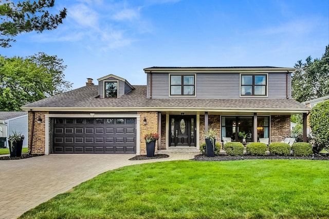 traditional-style home featuring brick siding, a front lawn, covered porch, decorative driveway, and a garage