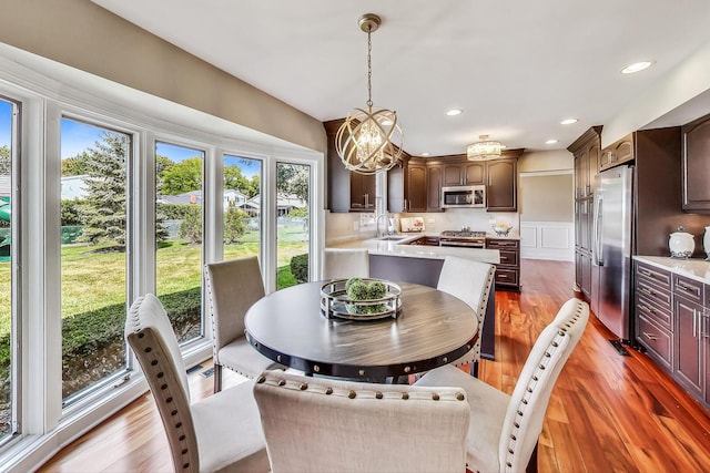 dining room with a decorative wall, recessed lighting, and light wood finished floors