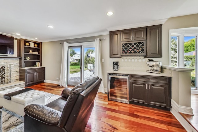 bar featuring plenty of natural light, wine cooler, light wood-style floors, a fireplace, and a dry bar