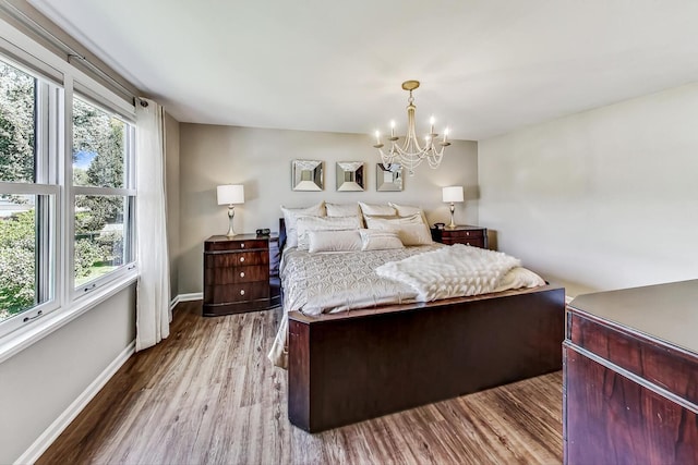 bedroom featuring an inviting chandelier, baseboards, and wood finished floors