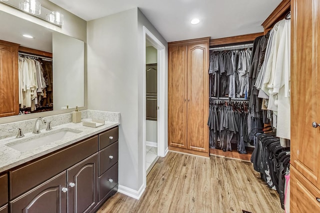 bathroom with wood finished floors, recessed lighting, baseboards, a spacious closet, and vanity