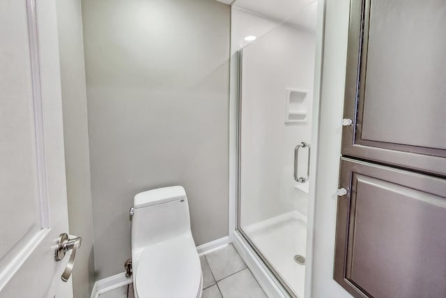 full bath featuring tile patterned flooring, a shower stall, toilet, and baseboards