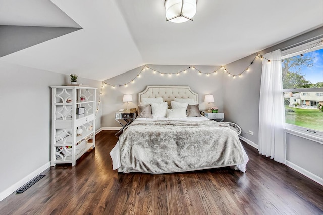 bedroom featuring visible vents, wood finished floors, baseboards, and vaulted ceiling