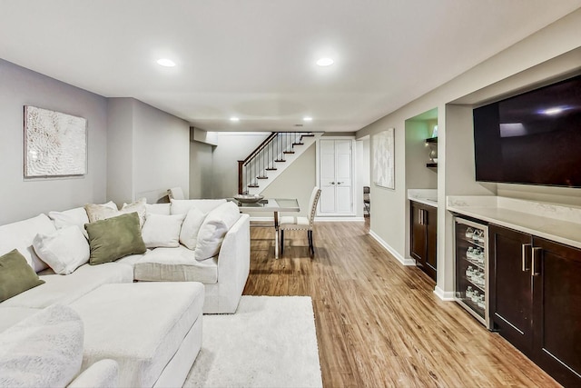 living room featuring stairway, beverage cooler, baseboards, light wood finished floors, and recessed lighting