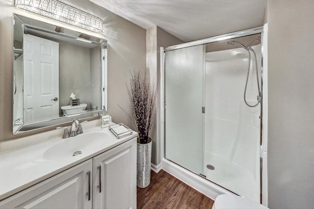 full bath featuring a stall shower, toilet, vanity, and wood finished floors