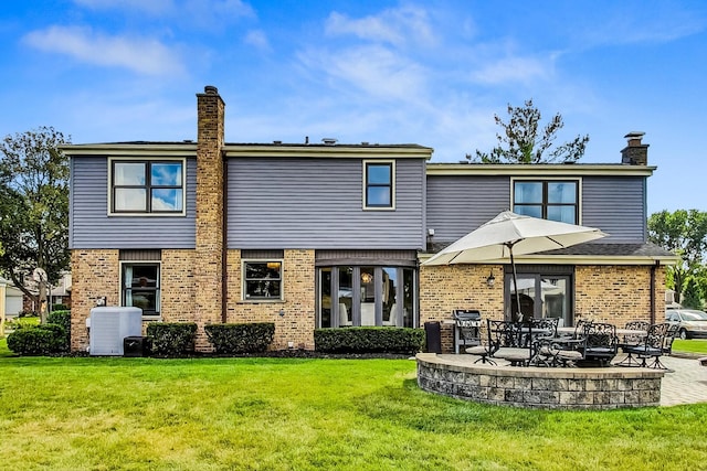 rear view of house with a yard, brick siding, central AC unit, and a chimney