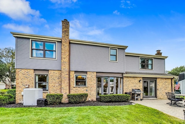 rear view of property with a patio area, central AC unit, a chimney, and a yard