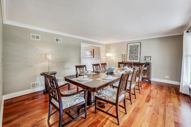 dining area featuring visible vents, crown molding, baseboards, and wood-type flooring