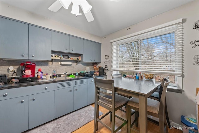 kitchen featuring decorative backsplash, dark countertops, light wood-style flooring, gray cabinets, and a sink