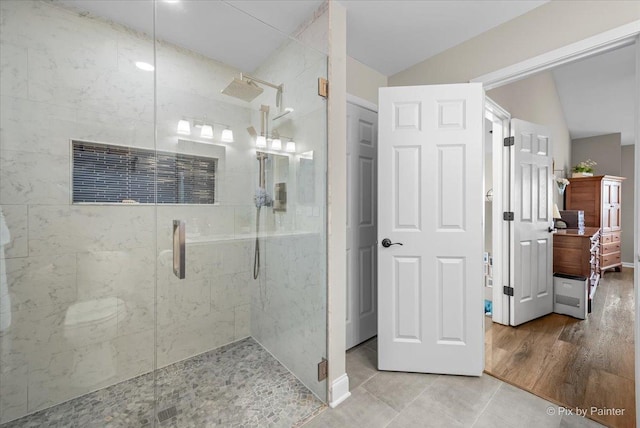 full bathroom featuring lofted ceiling, a shower stall, and wood finished floors