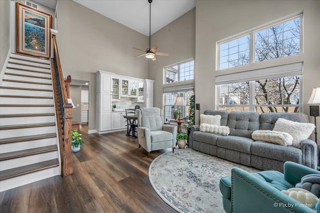 living room featuring a ceiling fan, dark wood finished floors, and stairs