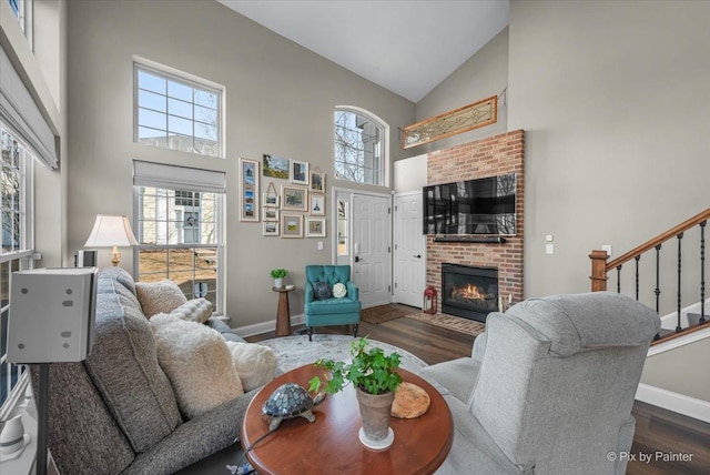 living room featuring high vaulted ceiling, a wealth of natural light, baseboards, and wood finished floors