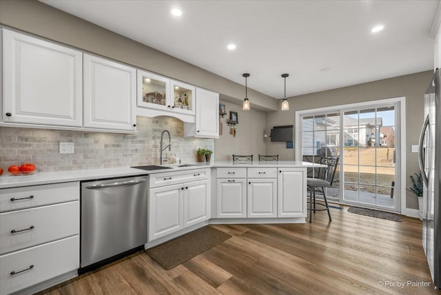 kitchen with appliances with stainless steel finishes, white cabinets, a sink, and a peninsula