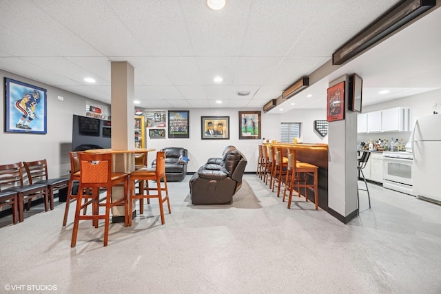 dining space with a bar, light speckled floor, a paneled ceiling, and recessed lighting