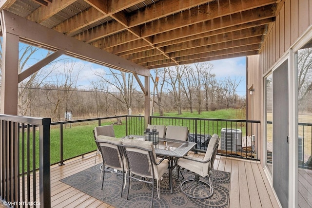 wooden deck featuring outdoor dining area and a lawn