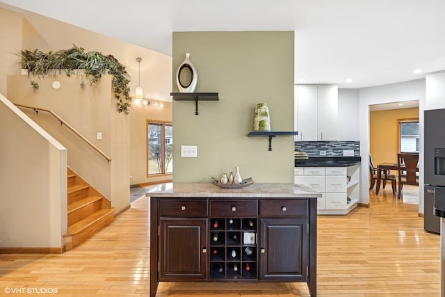 interior space with tasteful backsplash, light wood finished floors, dark brown cabinets, and open shelves