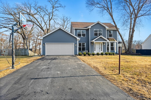 view of front facade with driveway, an attached garage, fence, and a front yard