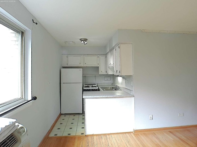 kitchen featuring range with gas stovetop, a wealth of natural light, light countertops, freestanding refrigerator, and a sink