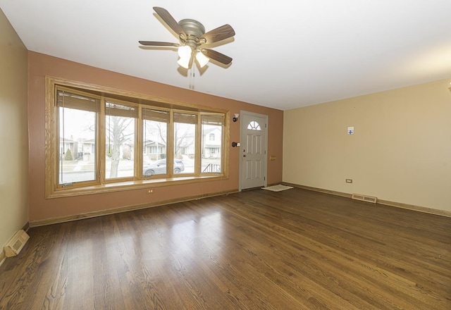 interior space with ceiling fan, baseboards, visible vents, and dark wood finished floors