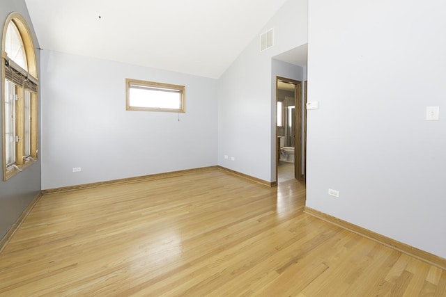 spare room with lofted ceiling, baseboards, visible vents, and light wood finished floors