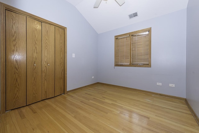 unfurnished bedroom with light wood finished floors, visible vents, a ceiling fan, vaulted ceiling, and baseboards