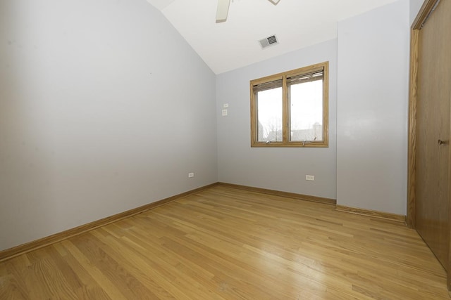 unfurnished room with light wood-type flooring, baseboards, visible vents, and lofted ceiling