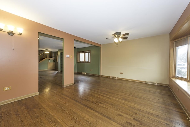 spare room featuring visible vents, ceiling fan, stairway, and wood finished floors