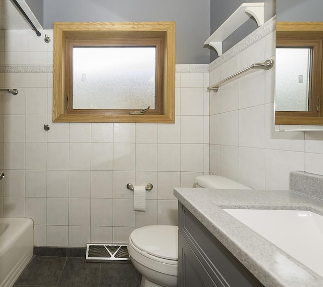 full bathroom with toilet, vanity, visible vents, and tile walls