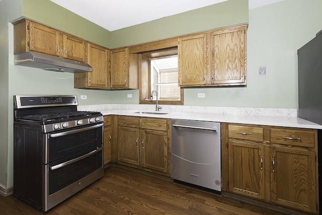 kitchen featuring stainless steel appliances, light countertops, dark wood-type flooring, a sink, and under cabinet range hood